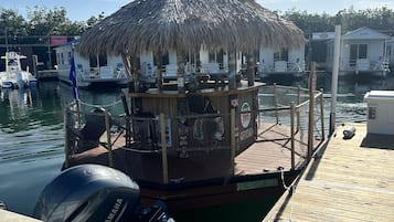 A docked boat with a thatched-roof structure, a Yamaha outboard motor, and a wooden deck.