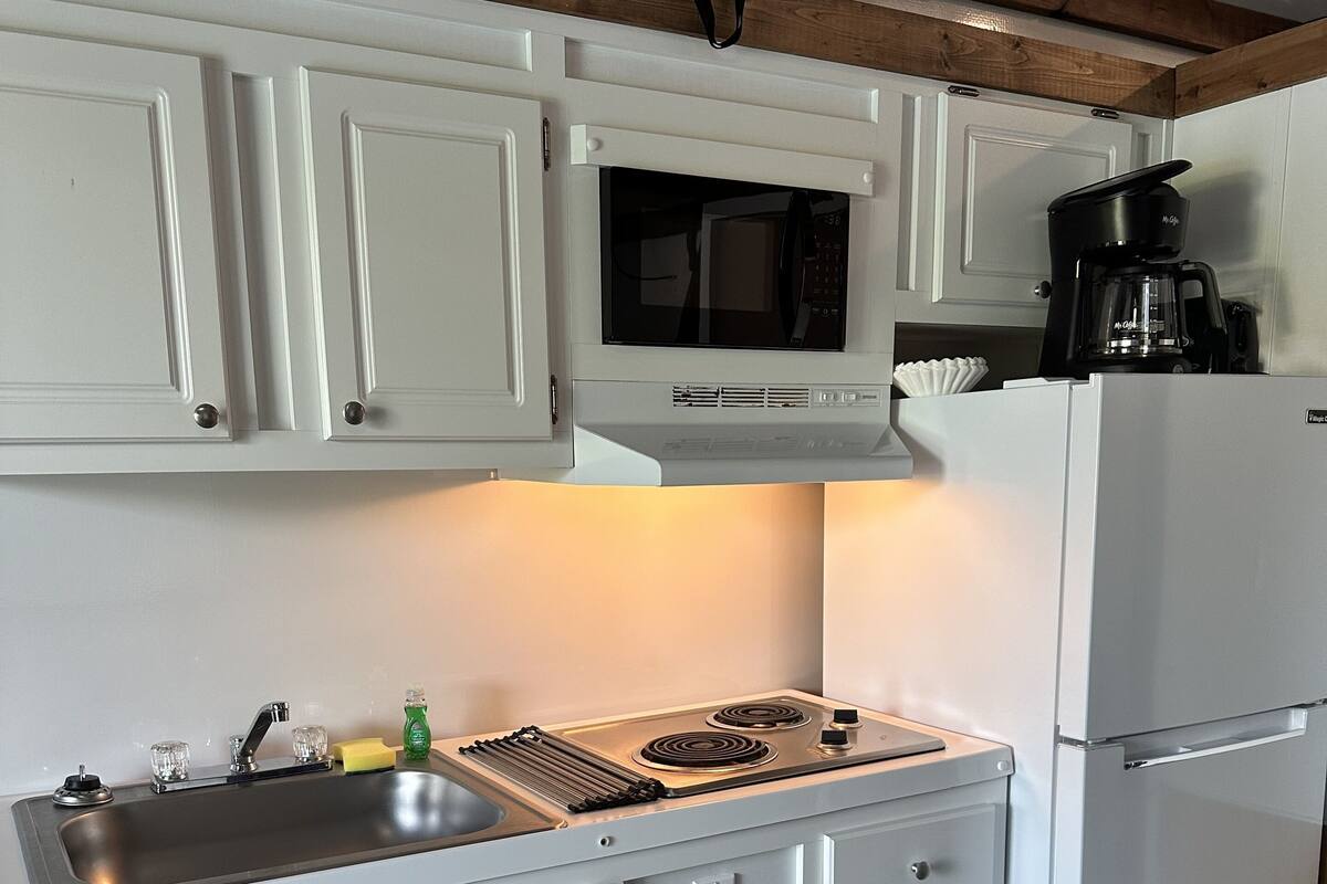 Une cuisine avec des meubles blancs, un four à micro-ondes, une cuisinière et un réfrigérateur.