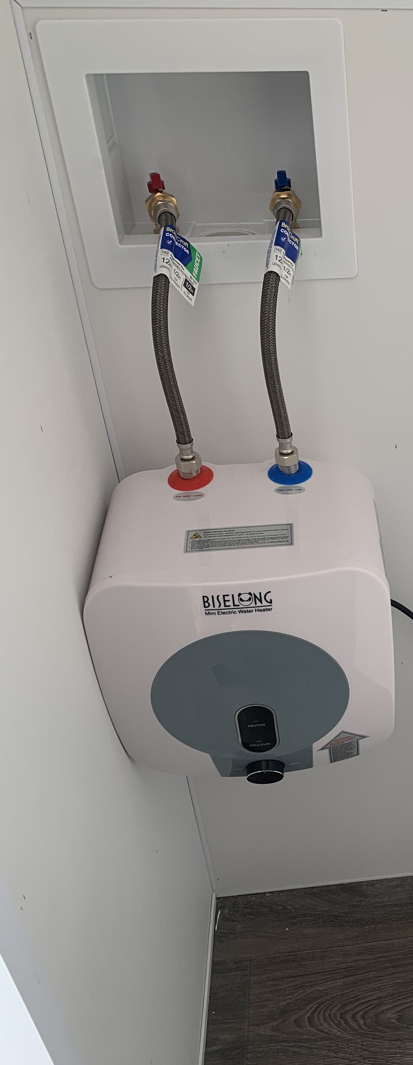 A BIELONG Mini Electric Water Heater with two hoses, one red and one blue, connected to a wall-mounted outlet.