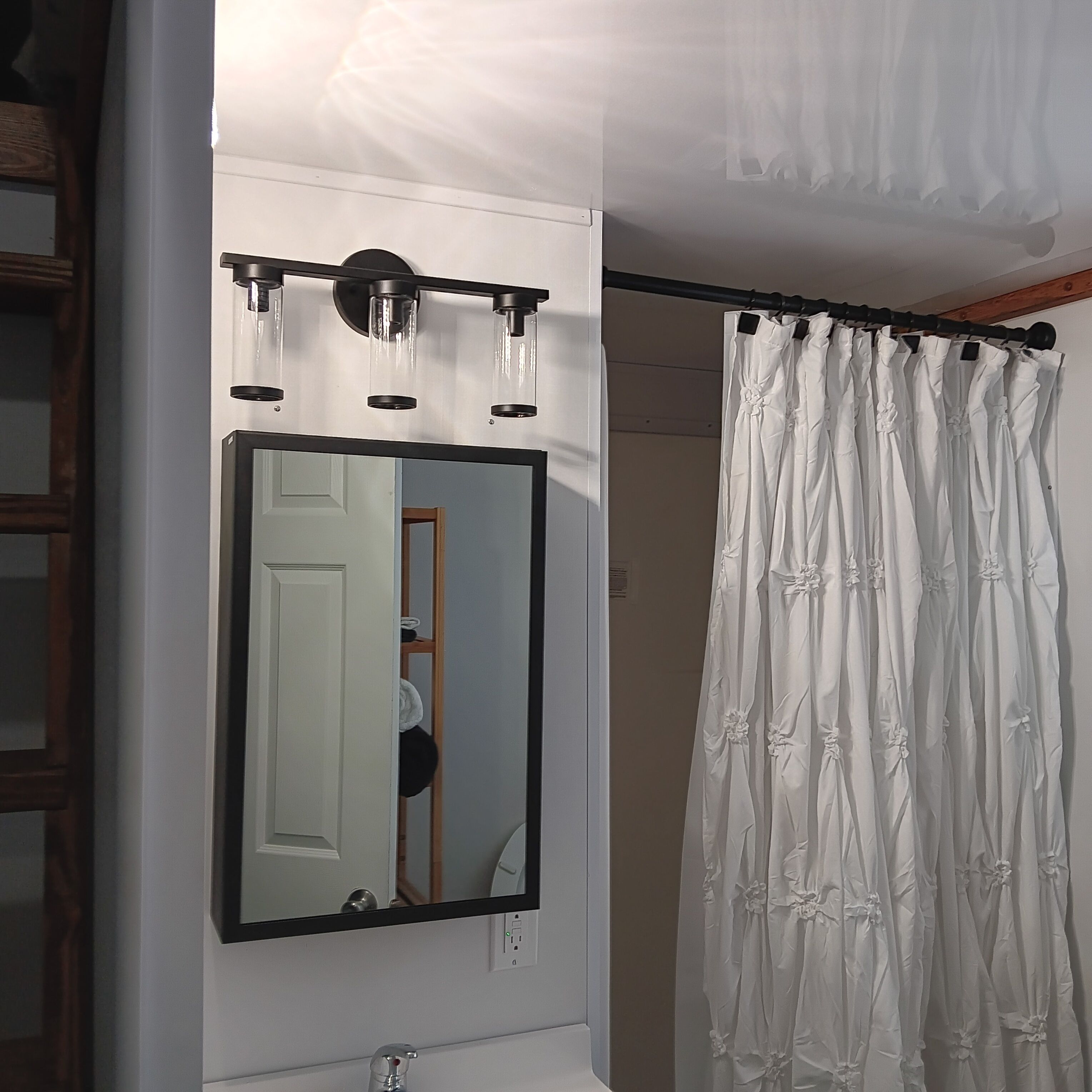 Un baño con espejo, lámpara y cortina de ducha.