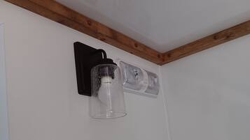 A corner wall with a black light fixture and two clear glass lampshades.