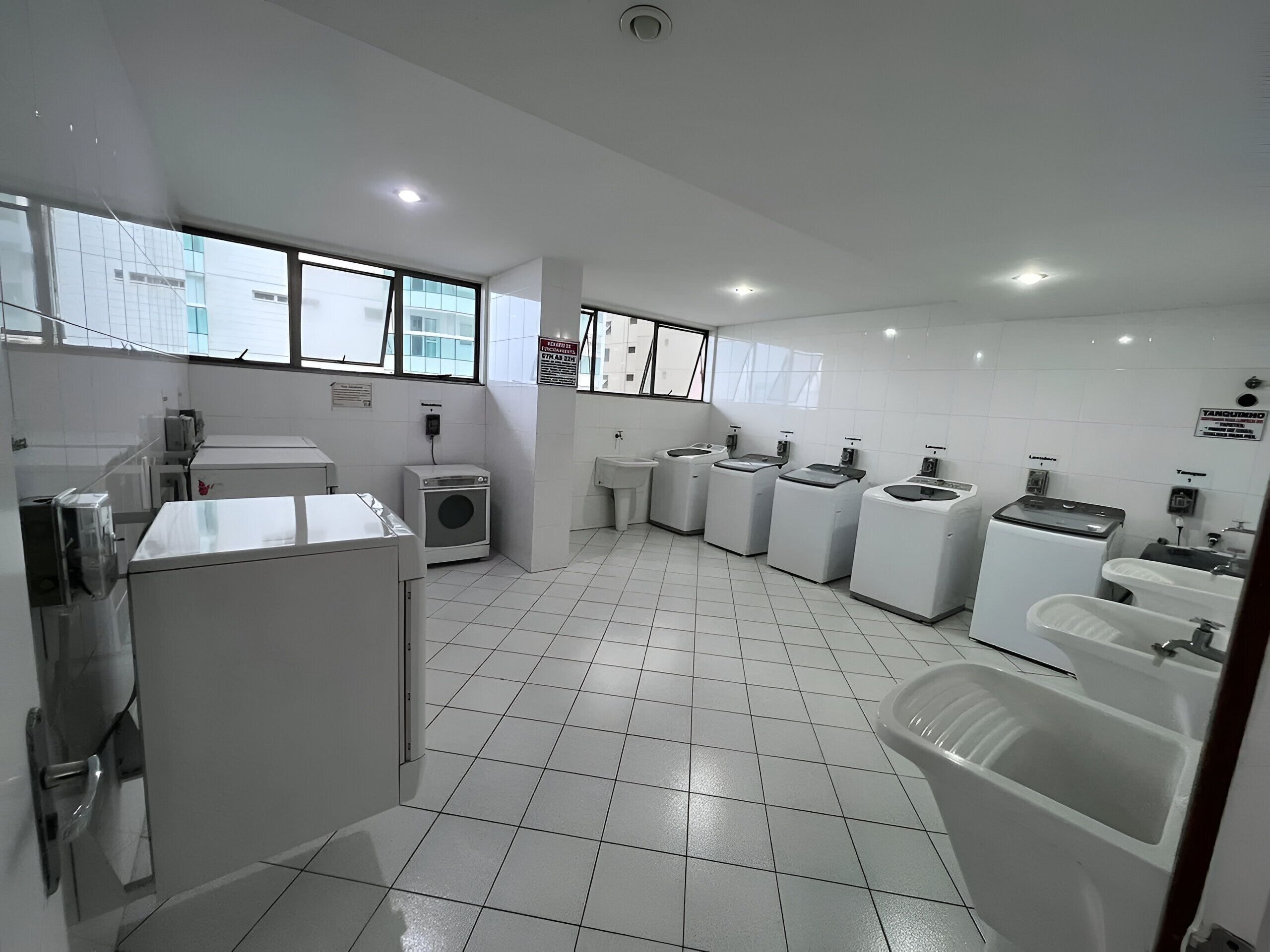 A modern kitchen with a large window, a washing machine, a sink, and a refrigerator.
