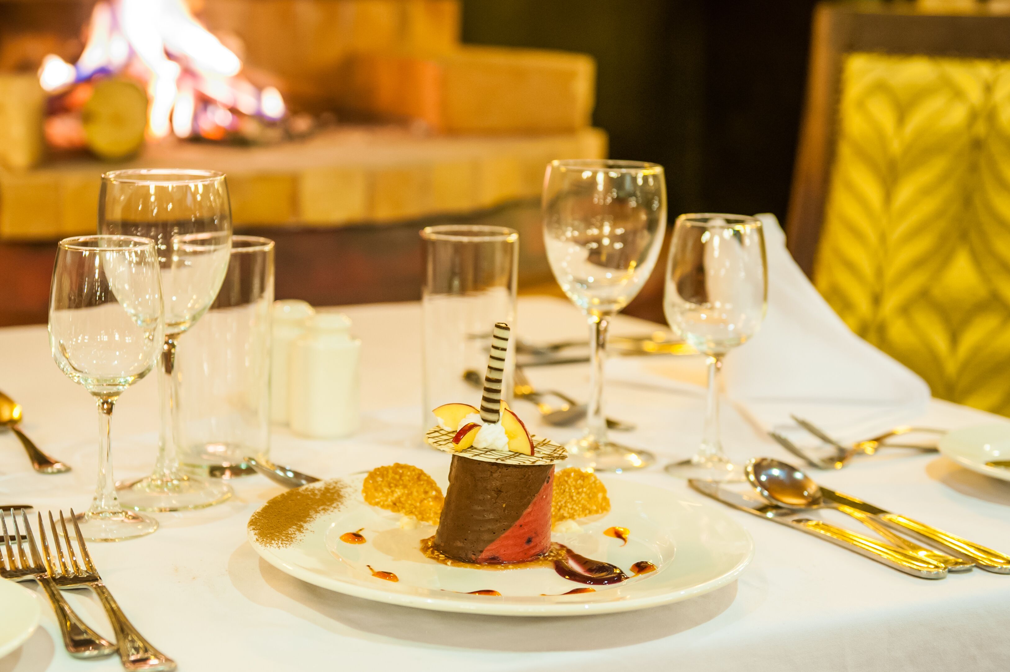 A table set for a meal with a dessert centerpiece, clear glasses, and silverware.