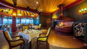 A restaurant with a wooden ceiling, a fireplace, and tables set for dining. - Lake Nakuru Sopa Lodge (Nakuru)