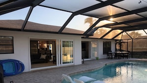 Un espace extérieur abrité avec une piscine, une terrasse, une porte-fenêtre coulissante donnant sur un espace intérieur et une piscine gonflable bleue.