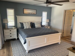 A bedroom with a white bed, patterned rug, and a ceiling fan. - Updated Private Tropical Retreat with Heated Pool and Spa, Great Gathering Space (Bonita Springs)
