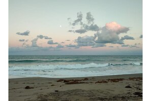 A beach with waves and a cloudy sky.