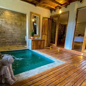 A wooden deck with a swimming pool, stone walls, and wooden doors.