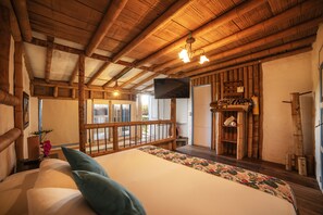 A wooden cabin-style bedroom with a large bed, a television, and a balcony.