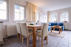A dining area with a wooden table and chairs, a blue sofa, and a white radiator.