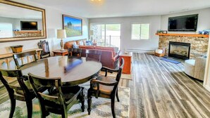 A spacious living room with a fireplace, a dining area with a large table, and a cozy seating area. - Ski-In Ski-Out Townhome | 2 Bedfroom | Shared Hot Tub | Fireplace | Parking (Mt. Crested Butte)