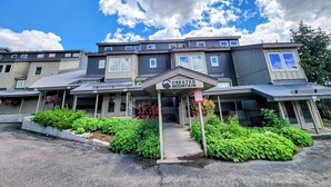 A multi-story hotel with a covered entrance, a sign reading "Crested Mountain," and a landscaped front yard. - Ski-In Ski-Out Townhome | 2 Bedfroom | Shared Hot Tub | Fireplace | Parking (Mt. Crested Butte)