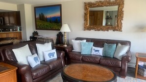 A living room with a brown leather sofa set, a round coffee table, and a painting of a landscape. - Ski-In Ski-Out Townhome | 2 Bedfroom | Shared Hot Tub | Fireplace | Parking (Mt. Crested Butte)