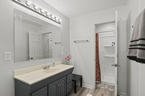 Een bad/douchecombinatie, een haardroger, handdoeken