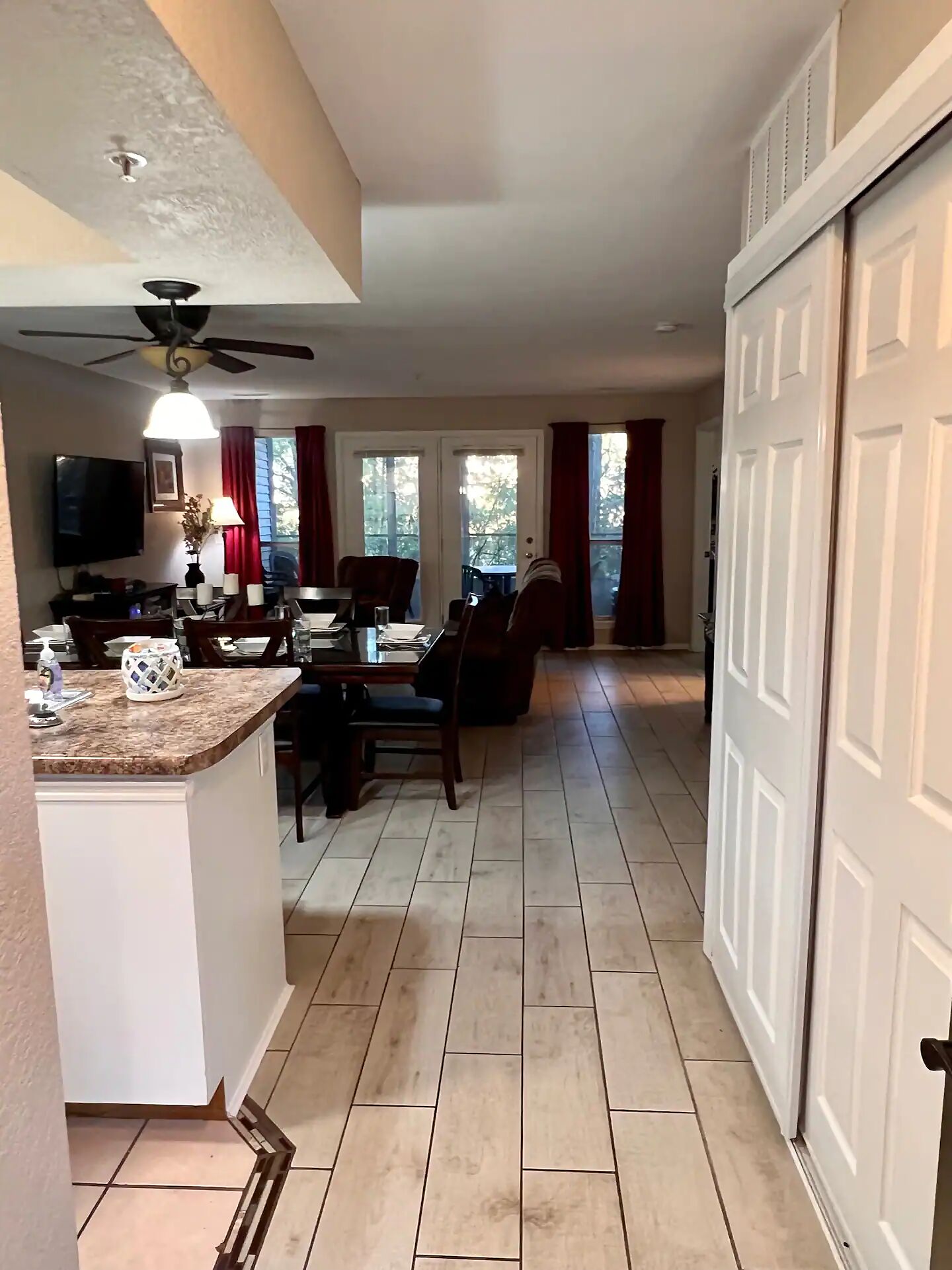 A spacious kitchen with a dining area, a ceiling fan, and a large window with curtains.