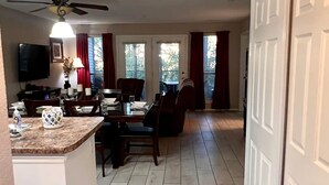 A spacious kitchen with a dining area, a ceiling fan, and a large window with curtains.