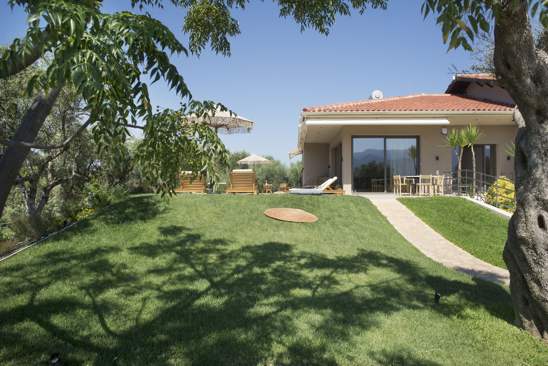 Une maison moderne dotée d’un patio couvert, d’une pelouse et d’un chemin menant à l’entrée.