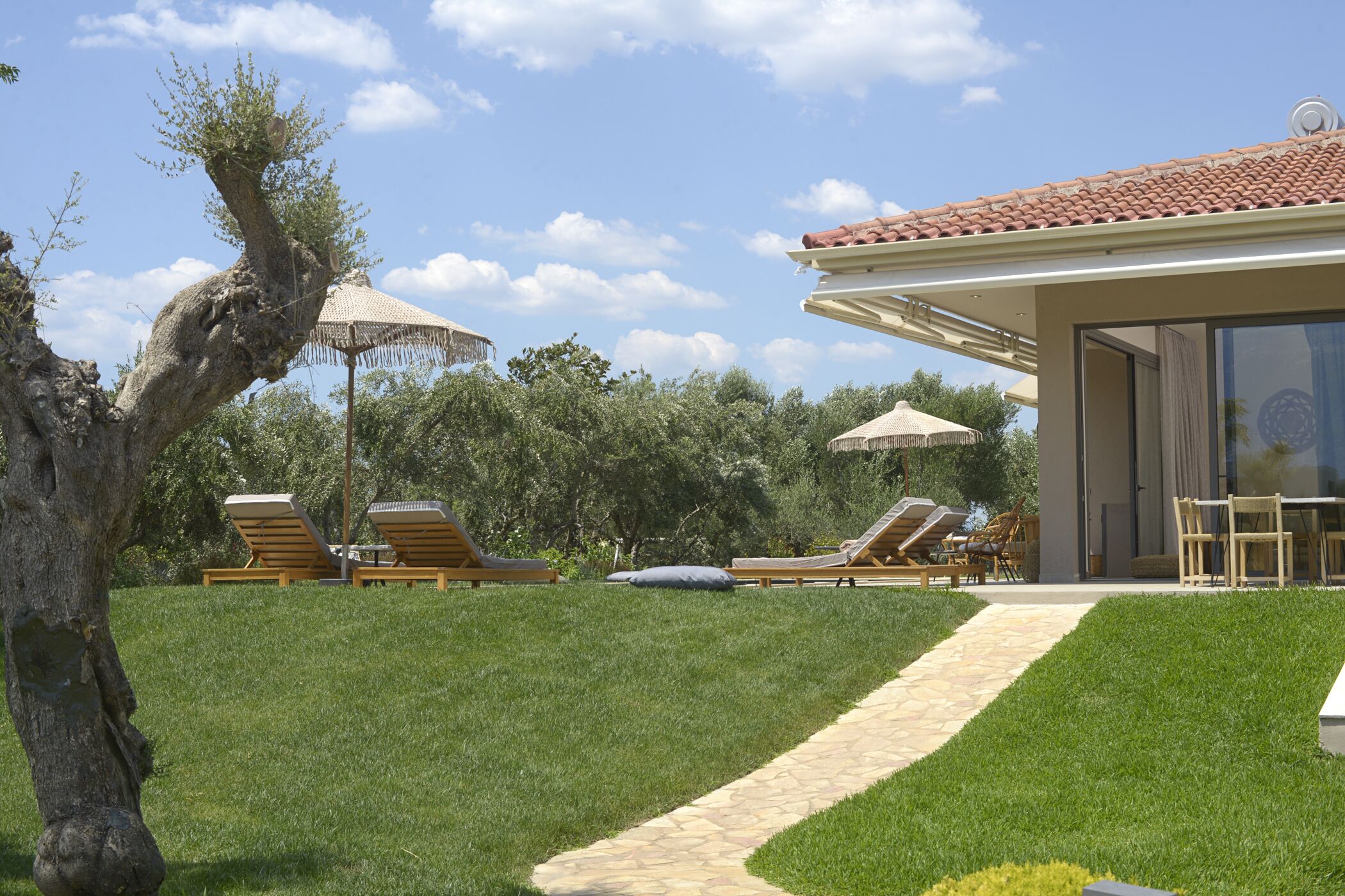 A modern outdoor area with a stone pathway leading to a building with a tiled roof.