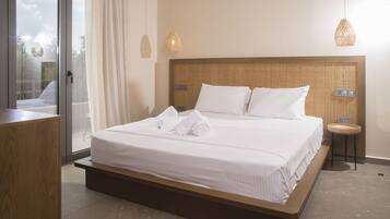 A neatly made bed with white linens and towels, a wooden headboard, and a small bedside table with a lamp.