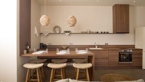Une cuisine moderne dotée d’un îlot central en bois, de tabourets de bar, de luminaires suspendus et d’appareils électroménagers intégrés.