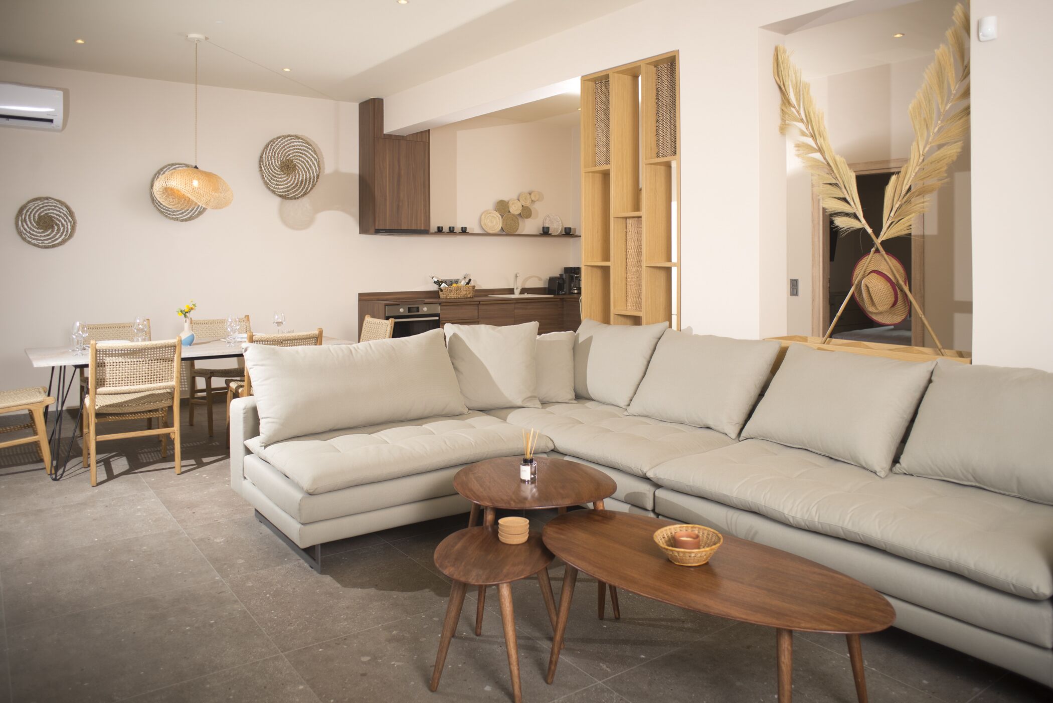 Una sala de estar moderna con un sofá modular, una mesa de comedor con sillas y una cocina al fondo.