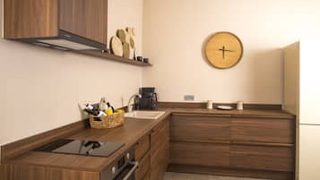Une cuisine moderne avec des meubles en bois, un four encastré, un évier et une horloge murale.