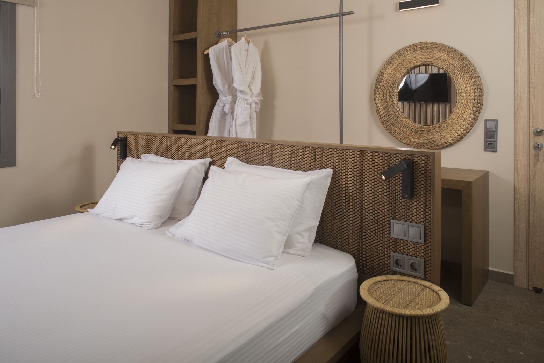 A neatly made bed with white linens, a bedside lamp, and a woven basket.
