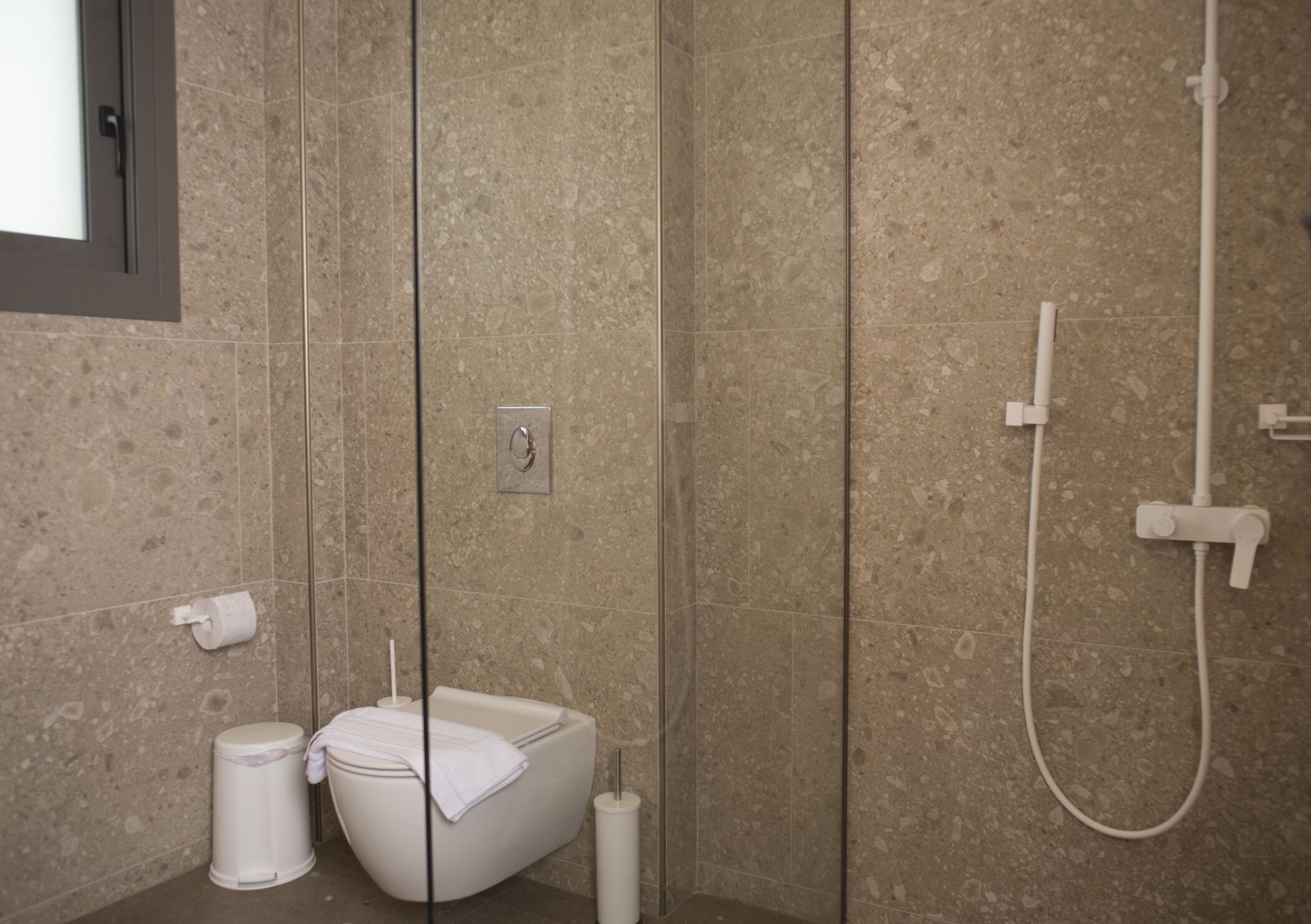 A modern bathroom with a freestanding toilet, a bidet, and a shower.