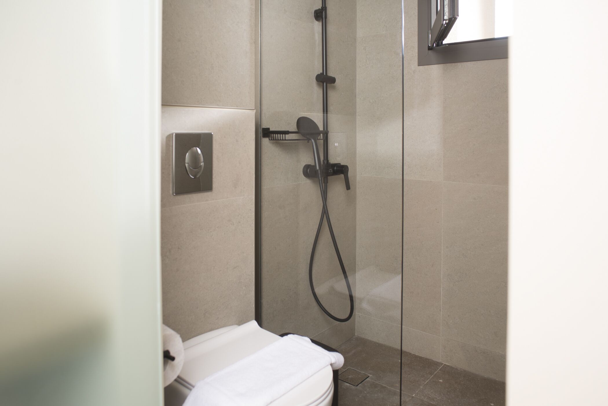 Une salle de bain moderne avec une douche à parois de verre, des toilettes et un porte-serviettes.