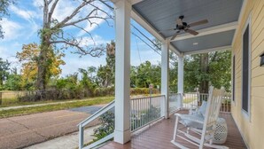 A covered porch with a rocking chair and a ceiling fan.