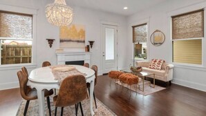 A dining room with a chandelier, a fireplace, and a sofa.