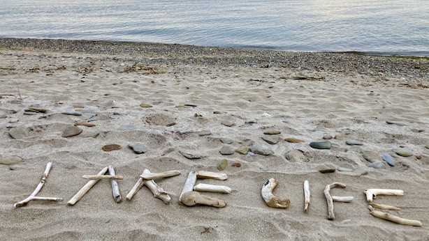 Une plage où les mots « LAKE LIFE » sont écrits avec des pierres.