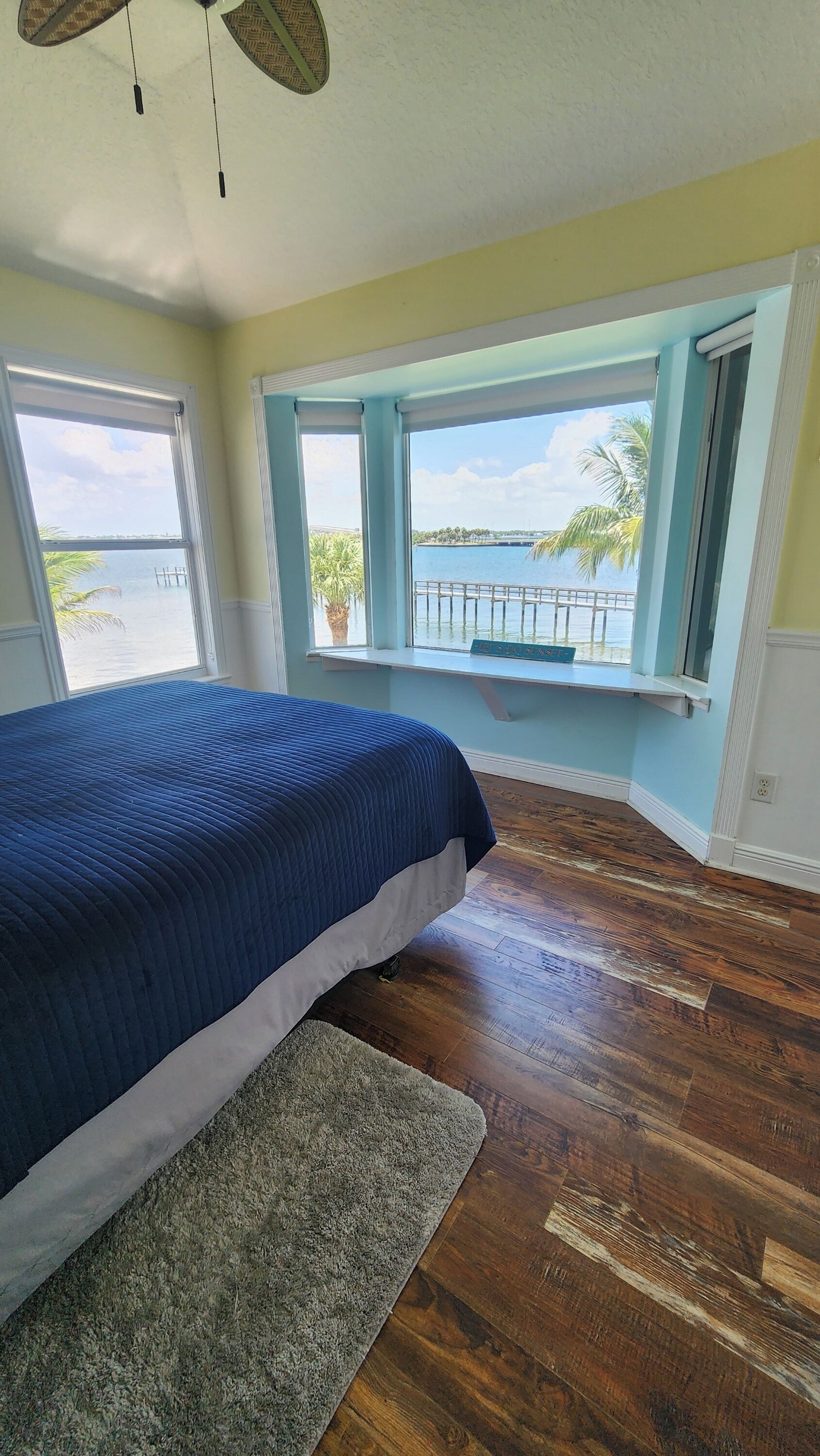 Une chambre avec un grand lit, une vue sur l’eau et un balcon.