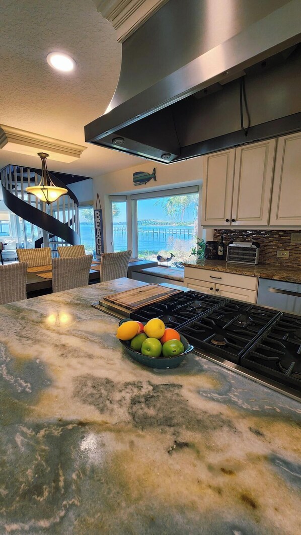 Una cocina con una isla central, vistas al exterior y una escalera en espiral.