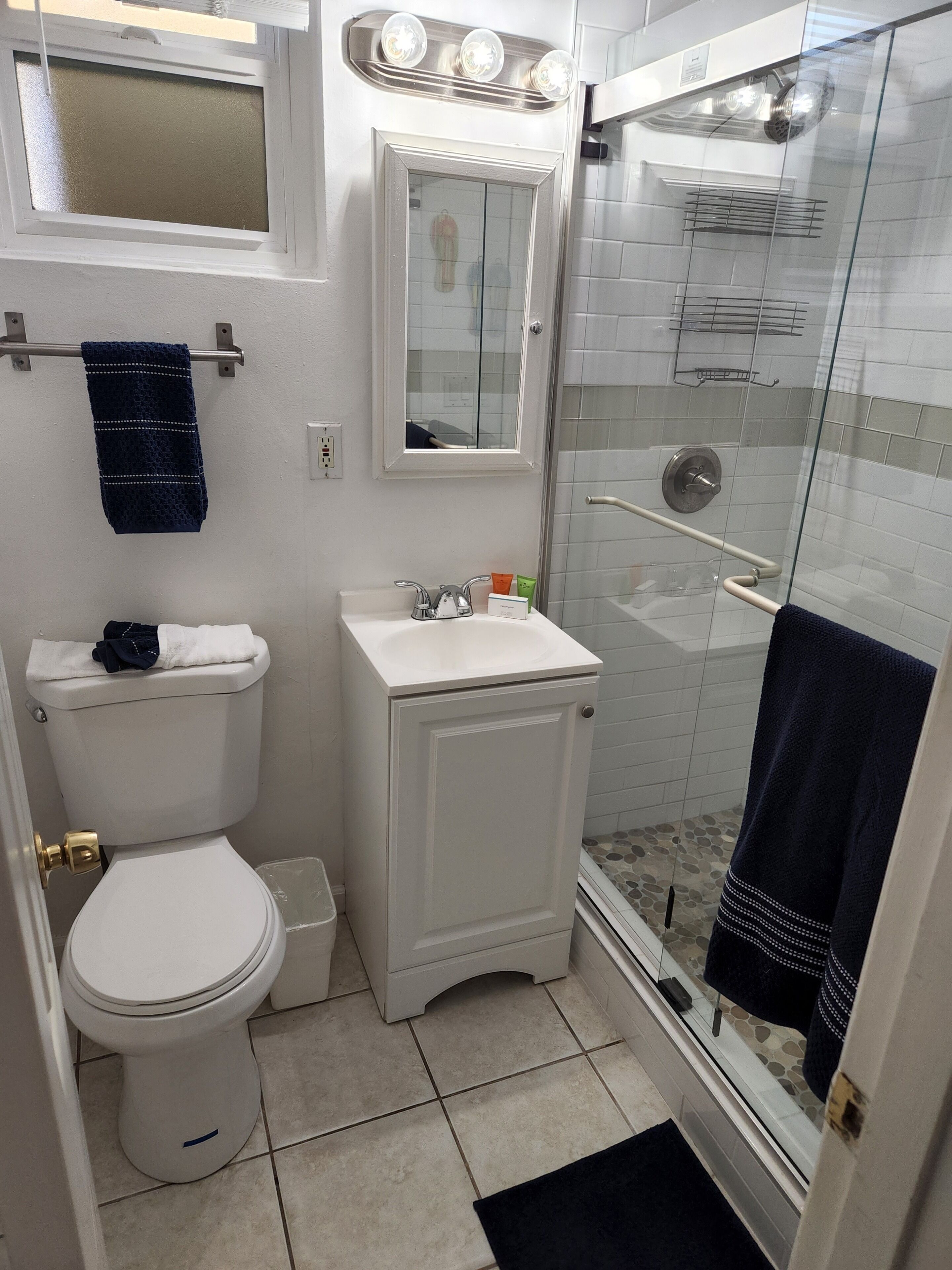 A compact bathroom with a toilet, sink, and glass shower enclosure.