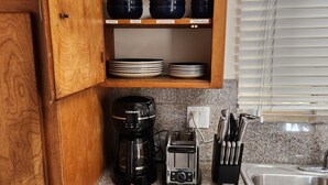 Una cocina con armarios de madera, cafetera, tostadora y fregadero.