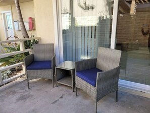 Relax in a serene outdoor space with two comfortable chairs and a table, surrounded by lush greenery.