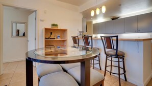 A modern kitchen with grey cabinets, a round glass table, and two bar stools. - Resort-Style Condo w/ Lake Chelan & Mtn Views (Chelan)