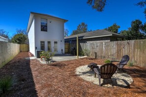 Uma casa de dois andares com varanda coberta e quintal cercado.