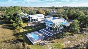 Un'ampia casa circondata da alberi e terreno aperto, con una piscina.
