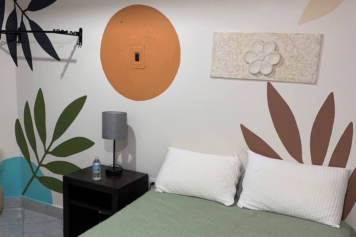 A hotel room with a bed, a nightstand, a lamp, and a wall decoration.
