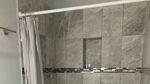 A modern bathroom with a shower area, tiled walls, and a toilet. - Residencial Edzna (Campeche)