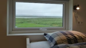 A bedroom with a window overlooking a grassy field.