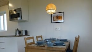 A modern kitchen with a wooden dining table, chairs, and a hanging light fixture.