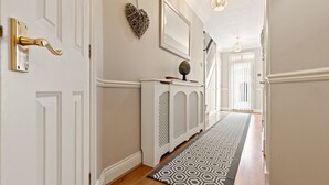 A hallway with a patterned rug, a white console table, and a heart-shaped decoration on the wall.