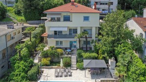 Ein mehrstöckiges Haus mit Swimmingpool, Sitzgelegenheiten im Freien und üppiger Bepflanzung.