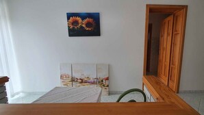 A bedroom with a bed, a wooden headboard, a painting of sunflowers, and a wooden wardrobe. - Holiday apartment near the beach with internet (Siófok)