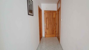 A narrow hallway with a wooden door at the end, tiled floor, and a framed picture on the wall. - Holiday apartment near the beach with internet (Siófok)