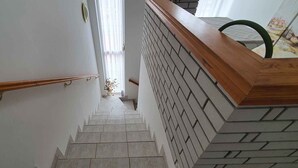 Eine Treppe mit Holzgeländer und einer Backsteinwand.