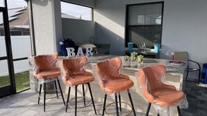 Un patio al aire libre con cuatro sillas cubiertas, una barra y vistas a paneles solares.
